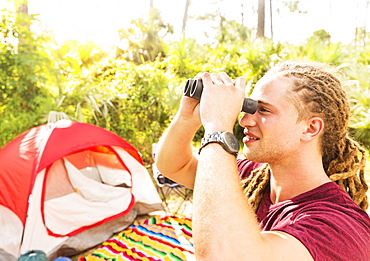 Young man watching birds through binoculars, Tequesta, Florida