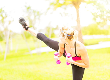 Young woman exercising in park using dumbbells, Jupiter, Florida