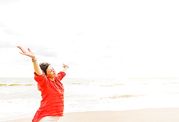 Side view of woman standing with arms up on beach, Jupiter, Florida