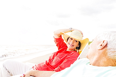 View of couple sitting in lounge chairs on beach, Jupiter, Florida