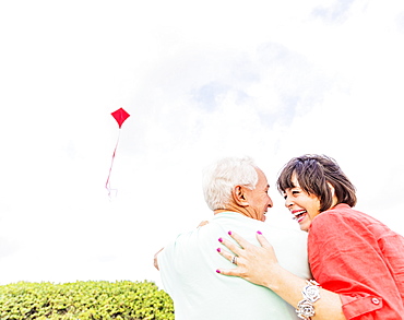 Low-angle view of couple flying kite together 