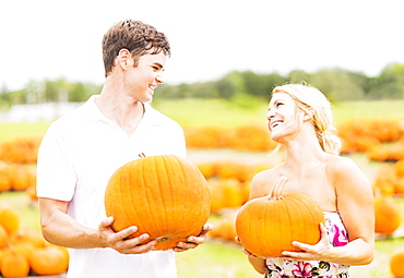 Portrait of young couple holding pumpkins, Jupiter, Florida