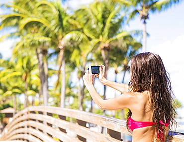 Young woman photographing wooden bridge, Jupiter, Florida