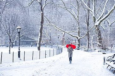 Woman walking with red umbrella on a snowy day