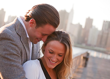 USA, New York, Long Island City, Young couple flirting on bridge, Manhattan skyline in background