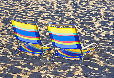 Empty beach chairs on sand