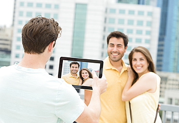 Man using tablet pc to take picture of friends