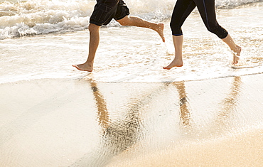 Couple running on beach, low section, Palm Beach, Florida