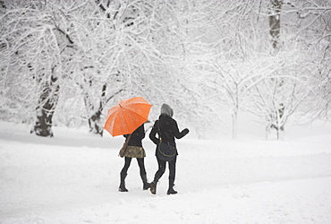 Two girls walking through snowy park