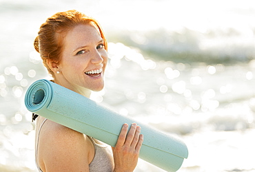 Portrait of woman holding yoga mat, Palm Beach, Florida