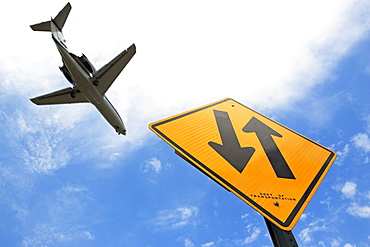 Airplane flying above down traffic sign
