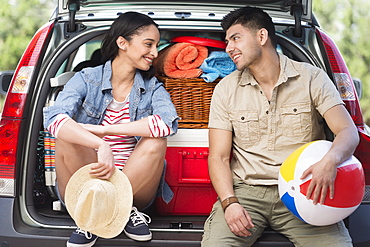 Young couple sitting in open car trunk