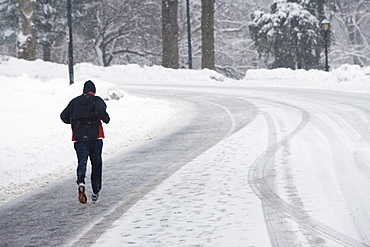 USA, New York City, man jogging up snowy road