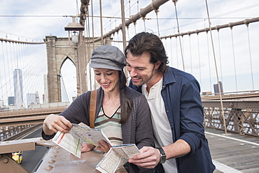 Happy couple reading map on Brooklyn Bridge, Brooklyn, New York