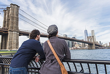 Couple leaning against railing and looking at Freedom Tower, Brooklyn, New York