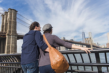 Couple leaning against railing and looking at Freedom Tower, Brooklyn, New York