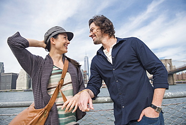 Happy couple standing and leaning against railing, Brooklyn, New York