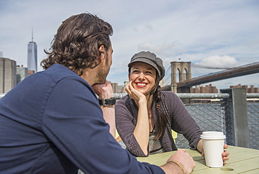 Happy couple sitting and discussing with cityscape in background, Brooklyn, New York