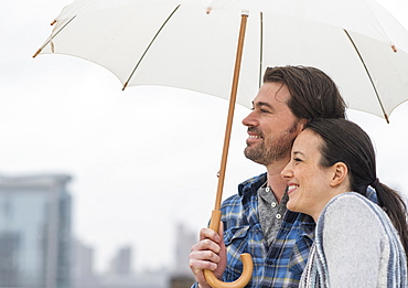 Side view of couple under umbrella