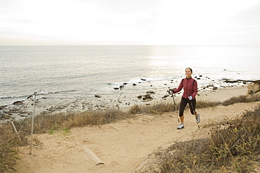 Hispanic woman pole walking along coast in California, United States