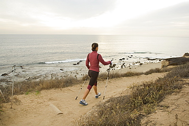 Hispanic woman pole walking along coast in California, United States