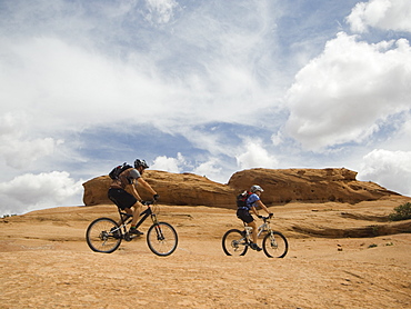 Couple riding mountain bikes in desert