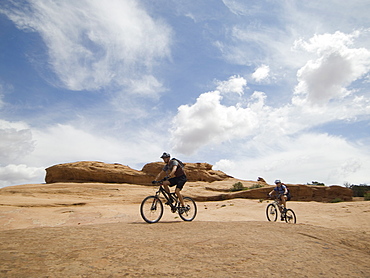 Couple riding mountain bikes in desert