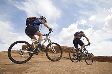 Couple riding mountain bikes in desert