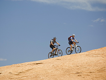 Couple riding mountain bikes in desert