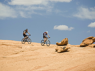 Couple riding mountain bikes in desert