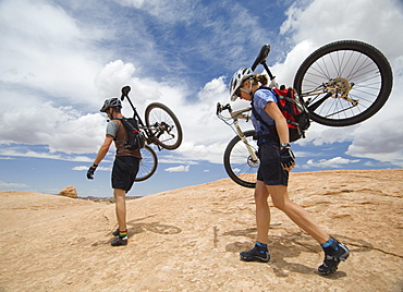 Couple carrying mountains bikes in desert