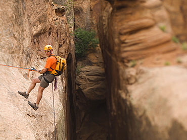 Man in rappelling gear at top of cliff