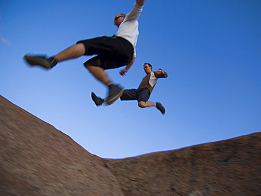 Men jumping over rock formations