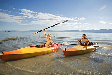 Brothers paddling in canoes on lake, Utah, United States