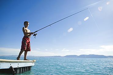 Boy fishing off dock in lake, Utah, United States