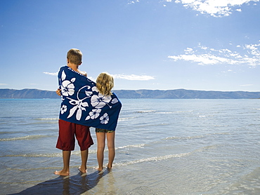 Brother and sister wrapped in beach towel, Utah, United States