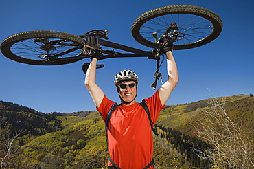 Man holding mountain bike over head, Utah, United States