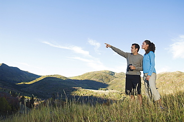 Couple holding binoculars and pointing, Utah, United States