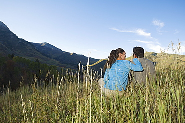 Couple sitting on hillside, Utah, United States