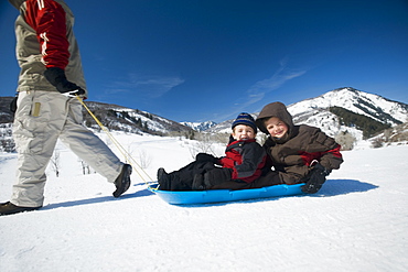 Father pulling children on sled