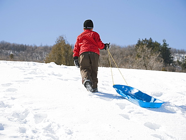 Boy pulling sled in snow