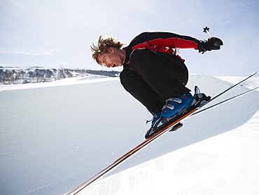 Skier jumping off lip of half-pipe