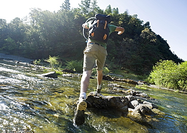 Man jumping across river on rocks