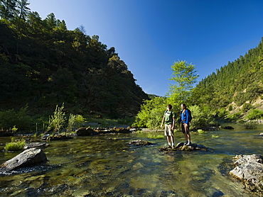 Hikers stranded on rock in middle of river