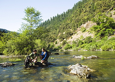 Hikers resting on rock in middle of river