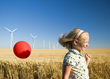 Girl holding balloon on wind farm