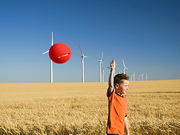 Boy holding balloon on wind farm