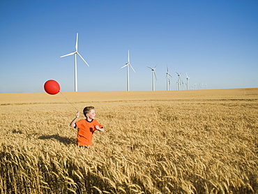 Boy running with balloon on wind farm