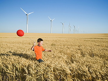 Boy running with balloon on wind farm