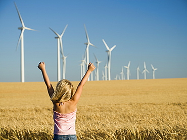 Girl with arms raised on wind farm